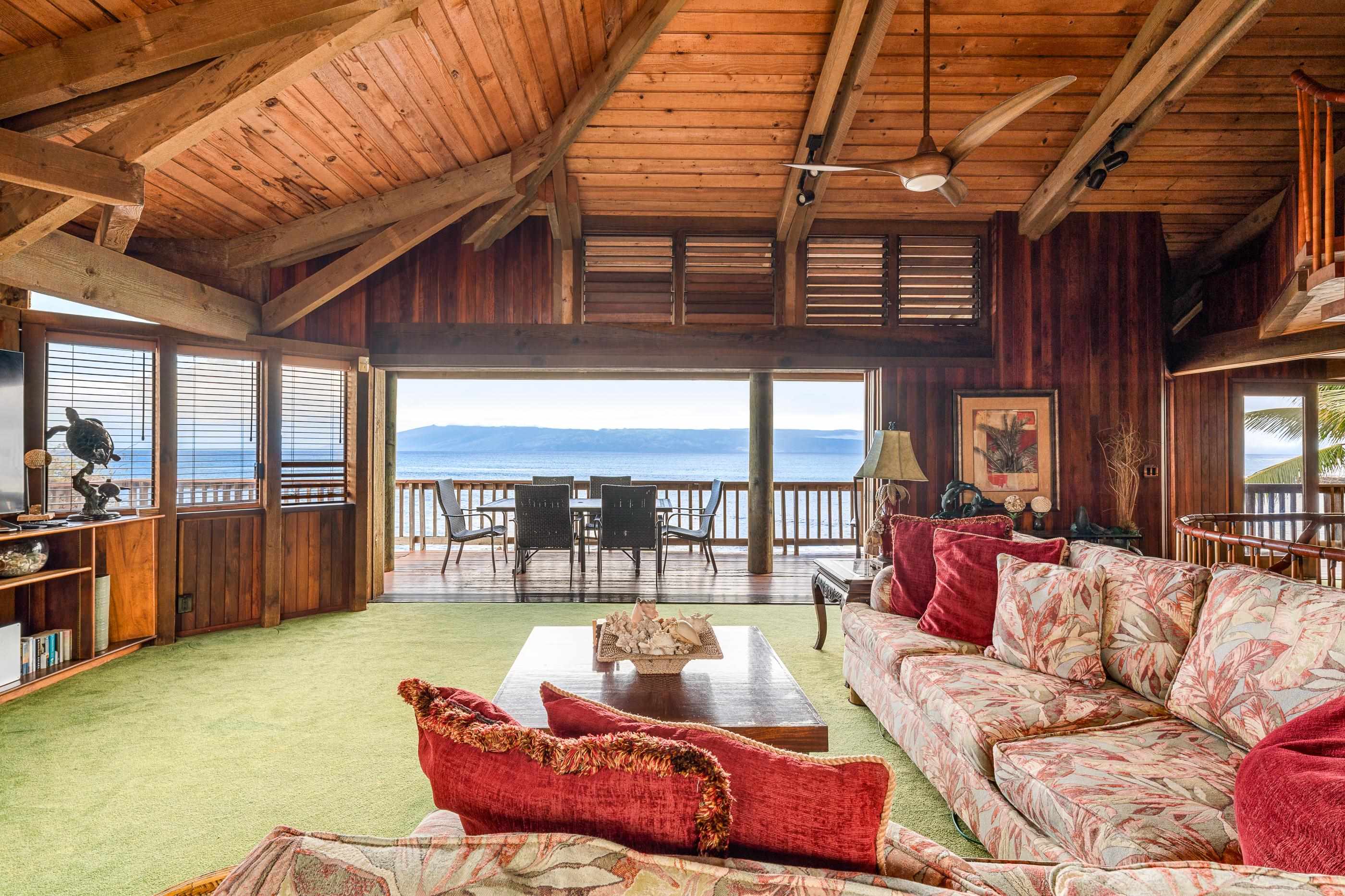 The great room's wall of glass, sofas facing the deck and the open ocean beyond