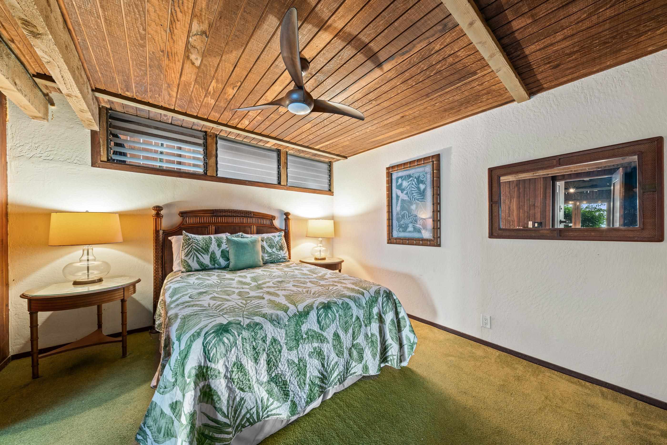 Bright bedroom with palm-leaf bedding, lamp table and mirror under the sloped ceiling